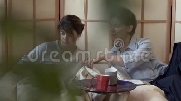 两个成熟的女人一起在家喝茶或喝咖啡一起在笔记本电脑上看信息两个优雅成熟的女朋友视频的预览图