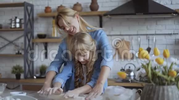 妈妈和女儿一起在厨房里烤披萨女孩帮她妈妈用擀面杖把面团卷出来4千克视频的预览图