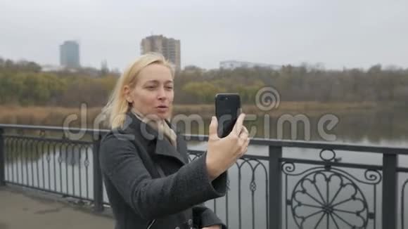一个走在桥上的女人在视频聊天有影响力的人制造智能手机相机视频的预览图