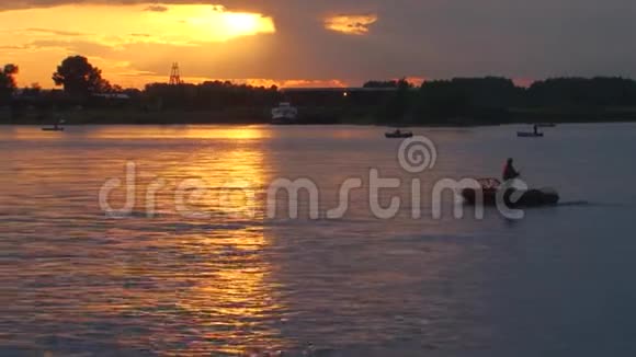 日落时人们在开阔的水面上从船上钓鱼马达锁交叉架视频的预览图