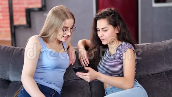 年轻女性与女友分享秘密看着智能手机屏幕聊天视频的预览图