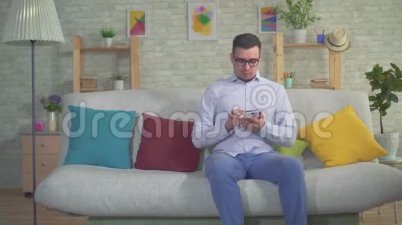 有智能手机的男人在家里沙发上癫痫发作视频的预览图