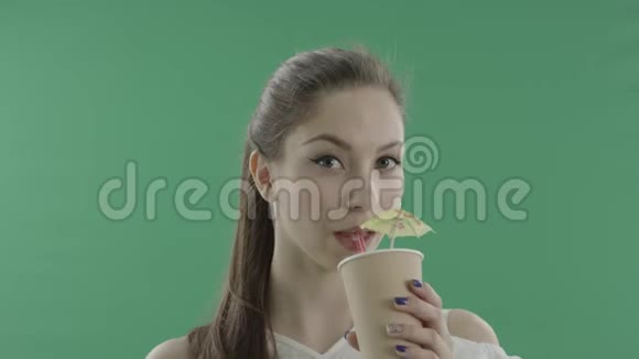 可爱的年轻女士在绿色背景下喝鸡尾酒视频的预览图