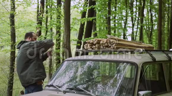 野生落叶林中随火柴和绳索在汽车附近作业的人的慢运动视频的预览图
