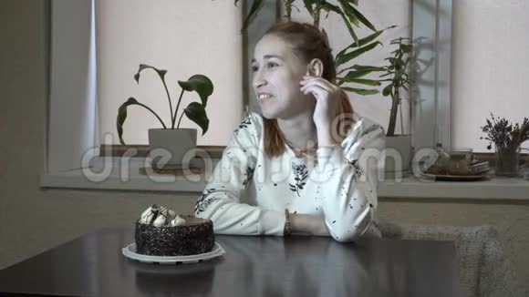 一位体贴的年轻女孩坐在厨房的桌子旁环顾四周等待着蛋糕视频的预览图
