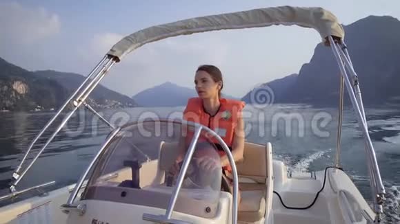 一个穿救生衣的漂亮女人开着一艘小船在湖边探险视频的预览图