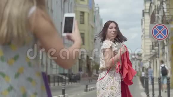 女孩照片在手机上快乐可爱的时尚女朋友户外快乐女孩炫耀她的新红视频的预览图