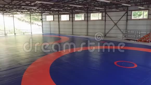 一个大型摔跤健身房没有人用垫子和蓝色覆盖橙色标记一块叫做t的武术地毯视频的预览图