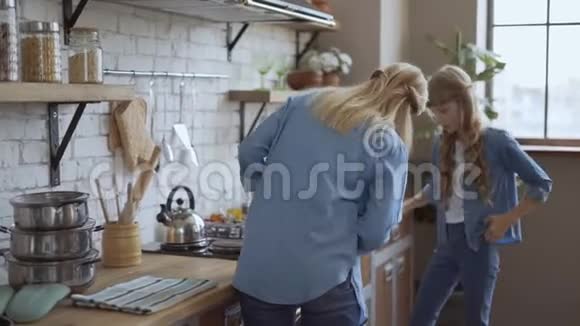 妈妈和女儿不耐烦地看着烤箱女孩子做美味可口的芳香自制晚餐4k视频的预览图