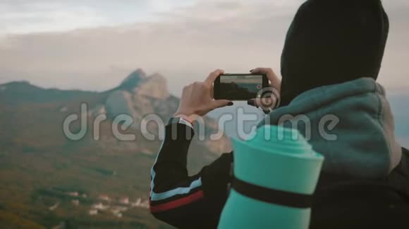 山顶上的女孩在手机上拍照的女游客年轻女性旅行者的背景视频的预览图