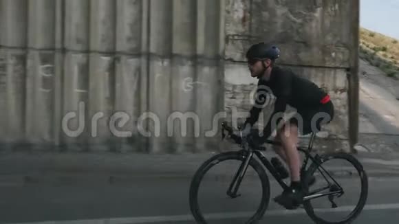 自信适合骑自行车的人骑自行车时戴着头盔黑色服装和太阳镜有胡子的自行车骑手骑自行车SS视频的预览图