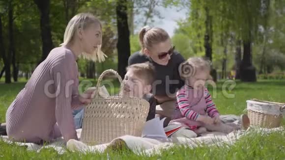肖像可爱的家庭户外娱乐两位年轻漂亮的母亲和他们的孩子在公园野餐一个男孩视频的预览图