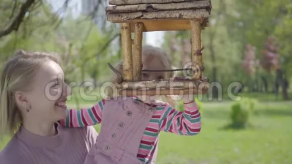 肖像年轻的母亲和女儿一起在公园里度过时光女人举起她的小女孩这样她就能看到视频的预览图