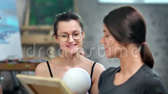 专业女画家在中等特写镜头中教授女学生素描球视频的预览图