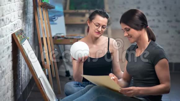 两位微笑的女画家在艺术学校学习从大自然中拿小球中射视频的预览图