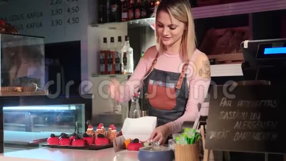 美丽的年轻女卖家正站在糖果店的柜台前打包蛋糕视频的预览图