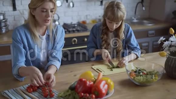 妈妈和女儿一起在一个明亮的大厨房做饭女孩帮妈妈切蔬菜幸福的家庭观念4千克视频的预览图