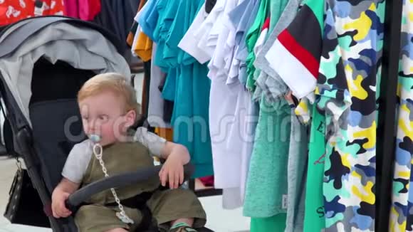 可爱的小男孩坐在服装店的婴儿车里视频的预览图