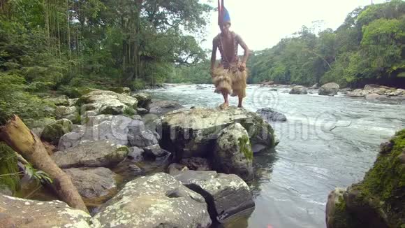 土著猎人在亚马逊雨林的石头上跳跃视频的预览图