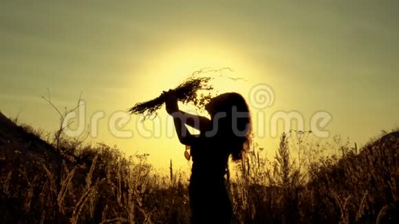 一个女孩的剪影在夕阳的明亮光线下手里拿着一束野花她嗅了嗅视频的预览图