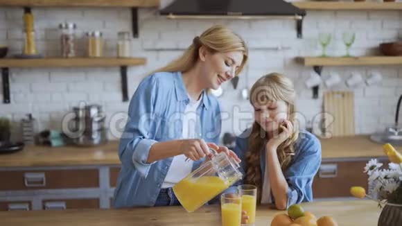 妈妈给女儿倒了一杯橙汁幸福的家庭在他们明亮的大家庭的餐厅里4千克视频的预览图