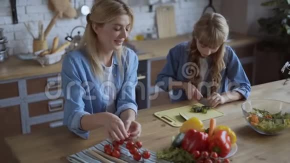 妈妈和女儿一起在一个明亮的大厨房做饭女孩帮妈妈切蔬菜幸福的家庭观念4千克视频的预览图