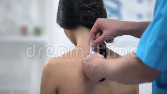 男性医生在女性患者上背部应用Y形磁带医疗保健视频的预览图