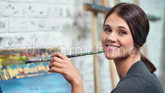 幸福的女画家摆姿势拿着彩色画笔看着镜头特写视频的预览图
