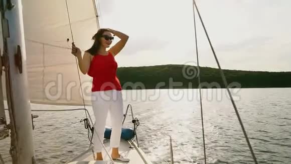 穿红白衣服的年轻女子站在帆船甲板上视频的预览图
