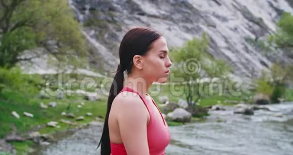 一位美丽迷人的女士在大自然中沉思的时候在河边的画像她享受着视频的预览图