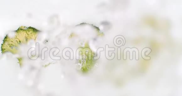 在慢动作中溅起的水花把水倒在美丽多汁的蔬菜上许多白底的西兰花视频的预览图
