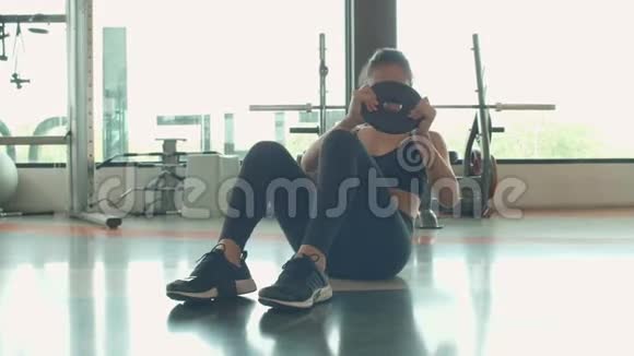 年轻的亚洲迷人的运动女性做纵横交错或扭转侧皱与杠铃重量板在健身健身房体育运动视频的预览图