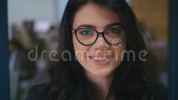美丽的微笑自信的年轻女子漂亮的脸看着办公室里的相机特写肖像戴眼镜视频的预览图