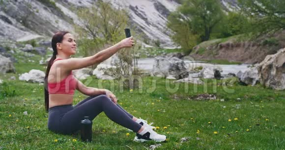 运动的女士在锻炼后在令人惊叹的景观中享受与自己自拍的时光视频的预览图