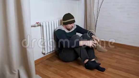 一个男人在家里戴着帽子和温暖的衣服沐浴在温暖的电池里寒冷的冬霜视频的预览图
