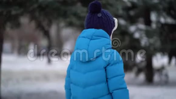 穿着蓝色冬装的可爱的四岁男孩走在雪地里视频的预览图