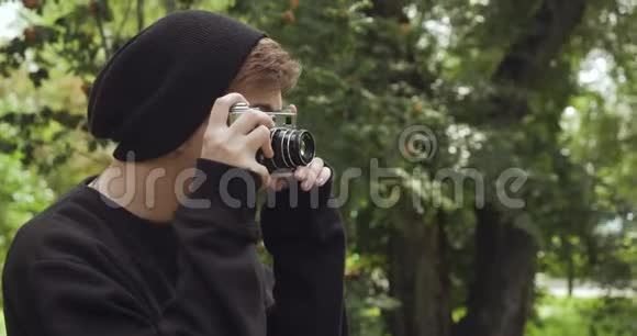 戴着黑色帽子的年轻潮人在老式相机上拍照视频的预览图