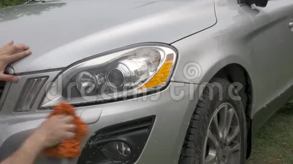 男人拿着海绵洗小心灰色掀背车灯视频的预览图