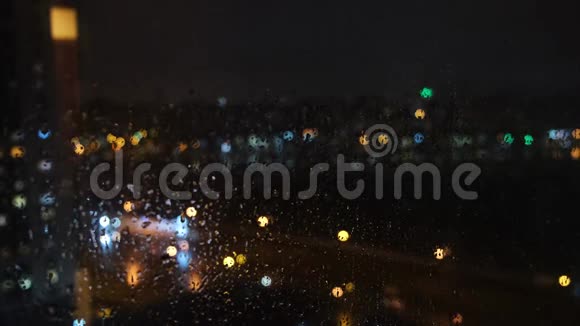 透过窗户看模糊的城市晚上雨滴落在玻璃上概念雨水视频的预览图