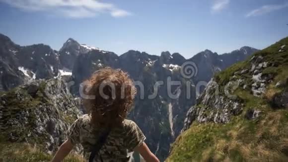 暑假里快乐的孩子站在悬崖边欣赏山的自然背景视频的预览图