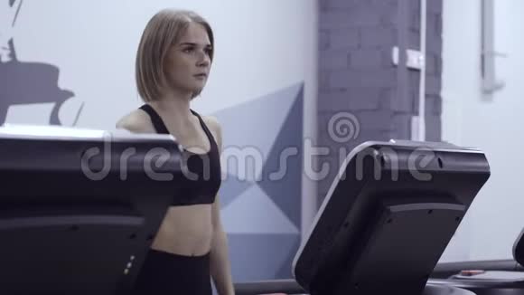 年轻运动的女人在健身房的跑步机上走得很快视频的预览图