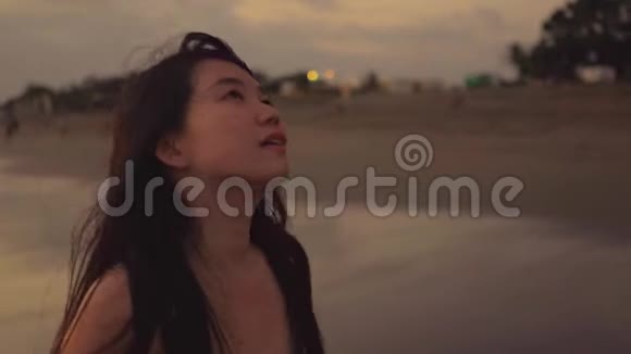 一系列年轻美丽快乐的亚洲韩国女人在日落的黄昏微笑着在海滩上悠闲地散步视频的预览图