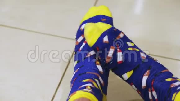 穿着蓝色和黄色的滑稽袜子用印刷的葡萄酒瓶人的腿概念舒适的家居服视频的预览图