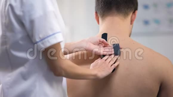 医生给病人上背部贴Y形磁带减少肌肉痉挛视频的预览图