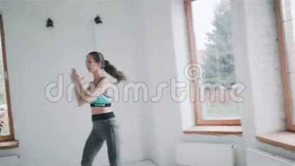 穿运动服装的年轻身材漂亮的黑发女孩在家做运动视频的预览图
