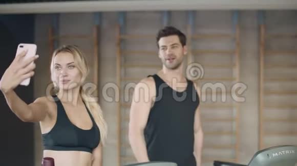 严肃的女性在健身训练中摆出移动照片男人做了肯定的手势视频的预览图