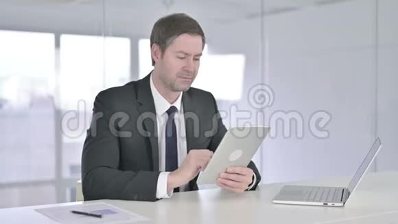 中年商人在办公室里用平板电脑聊天视频的预览图