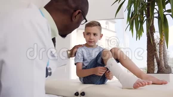 非洲医生和腿上带绷带的小病人谈话视频的预览图
