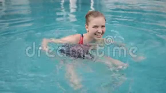 快乐的青少年女孩带着牙套在游泳池里游泳视频的预览图