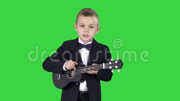 穿着服装的男孩在绿色屏幕上行走和演奏四弦琴Chroma键视频的预览图